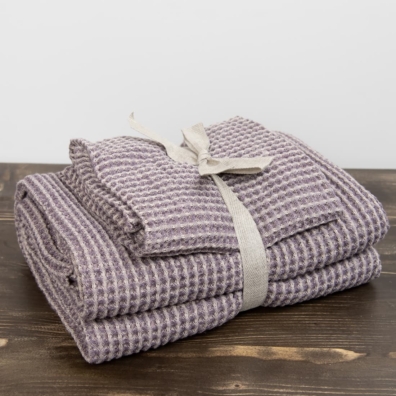 Sett med beige-lilla håndklær er bundet med et bredt bånd